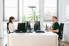 Zwei Personen sitzen an einem hellen und modernen Büroarbeitsplatz