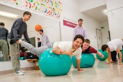 Junge Menschen haben Spaß beim Trainieren von Übungen auf Gymnastikbällen.