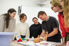 Gruppe von Auszubildenden zum Heilerziehungspfleger üben das Wickeln eines Babys an einer Puppe.