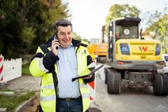 Ein Mann in Sicherheitsuniform telefoniert auf einer Baustelle