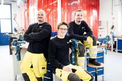 Drei Azubis gemeinsam in der Werkstatt – ein Team von Mechatronikern, die ihre praktischen Fähigkeiten in der technischen Ausbildung entwickeln.
