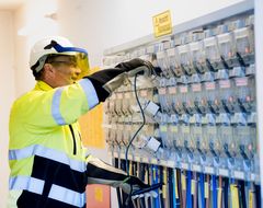 Eine Elektrofachkraft mit Sicherheitsanzug und Helm, arbeitet an Sicherungen