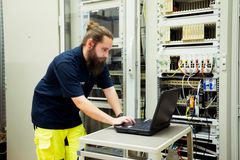 Eine Elektrofachkraft arbeitet an einem Laptop vor einer Rundsteueranlage.