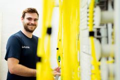 Ein Elektrofachmann schaut lächelnd in die Kamera während er am Schaltschrank arbeitet. 