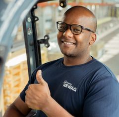 Ein Lagermitarbeiter der REWAG in einem Gabelstapler sitzend und Daumen nach oben zeigend.