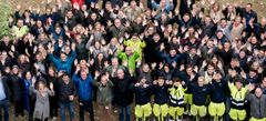 Das Bild zeigt viele Mitarbeiter der REWAG, wie sie nach oben schauend und winkend in die Kamera lächeln