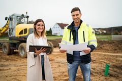 Dieses Bild zeigt einen Mann und eine Frau, die auf einer Baustelle stehen und lächelnd in die Kamera schauen.