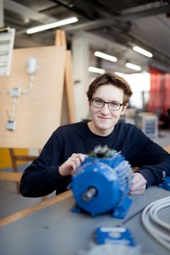 Das Bild zeigt einen lächelnden Mann der in die Kamera schaut und an etwas arbeitet. Das Bild soll auf die Ausbildung zum Mechatroniker bei der REWAG hinweisen