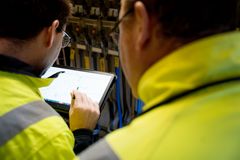 Ein Monteur prüft eine Anlage mit seinem Tablet.