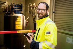 Eine Elektrofachkraft mit gelber Sicherheitsweste vor einer Hochsicherheitsanlage