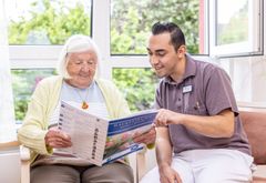 Bewohnerin und Mitarbeitender lesen in der Hauszeitung