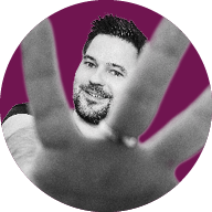 Ein lächelnder Mann streckt seine Hand in den Vordergrund in Richtung Kamera; das Bild ist in Schwarz-Weiß gehalten mit einem farbigen Hintergrund.