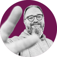 Ein lächelnder Mann mit Brille und Bart streckt seine Hand in den Vordergrund in Richtung Kamera; das Bild ist in Schwarz-Weiß gehalten mit einem farbigen Hintergrund.