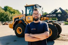 Männliche Person im Vordergrund, gelber Traktor im Hintergrund