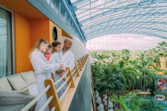 Familie mit zwei Kindern auf einem Balkon mit Blick auf Palmen