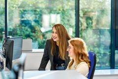 Zwei Frauen schauen zusammen im Büro auf einen Computer Monitor