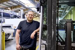 Ein Mann lehnt sich gegen einen Gabelstapler in einer Werkshalle