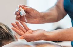 Kosmetikerin träufelt Massegöl in ihre linke Hand