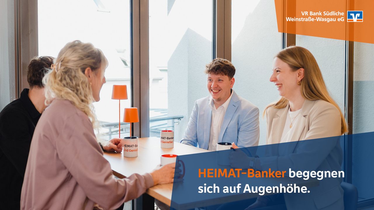 Vier Personen lachen im Gespräch an einem Tisch mit HEIMAT-Banker-Tassen, Text: „HEIMAT-Banker begegnen sich auf Augenhöhe“.