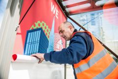 Service-Mitarbeiter von Wall hängt ein Plakat in eine Werbeanlage