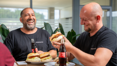 Zwei männliche Kollegen in der Mittagspause am lachen während sie Burger essen