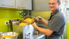Koch an der Fritteuse mit Pommes