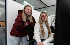 Eine Mitarbeiterin arbeitet eine neue Kollegin am Computer ein